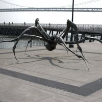 A giant spider statue next to a bridge.